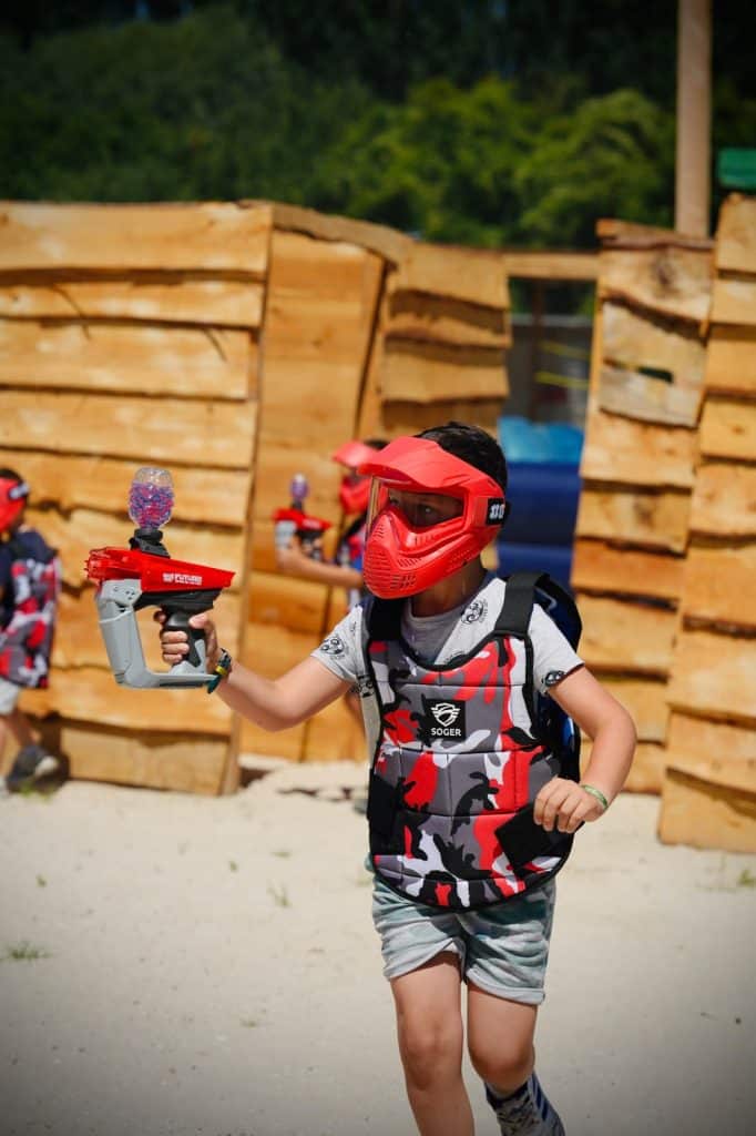 Un enfant portant un casque rouge qui joue au gellyball à Amiens dans un espace extérieur couvert.